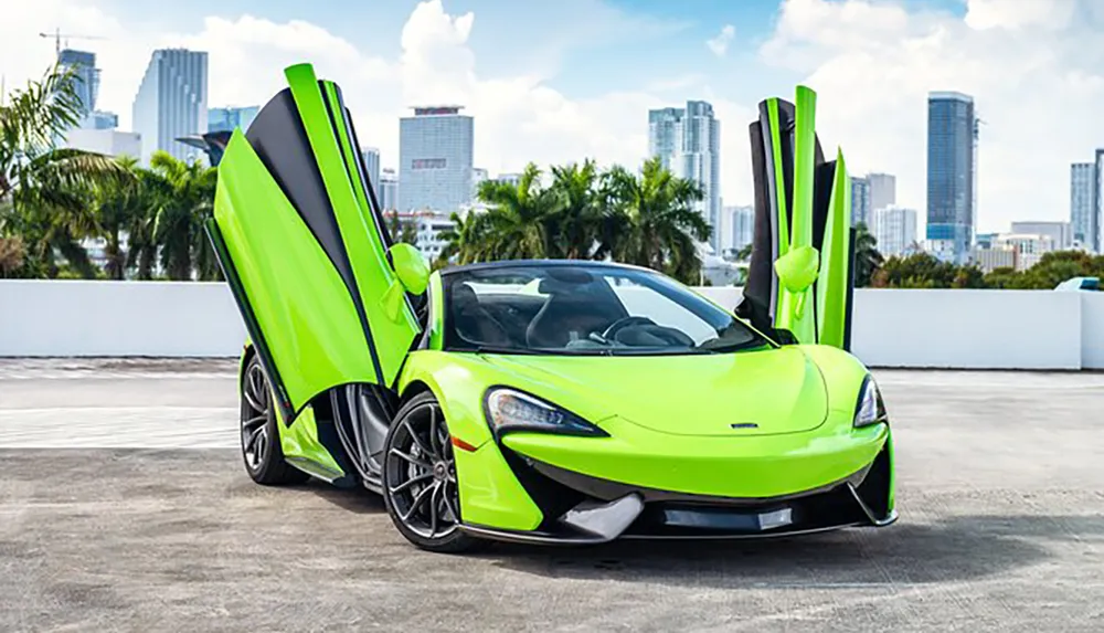 A bright green sports car with its doors open upwards is parked with a backdrop of high-rise buildings under a blue sky