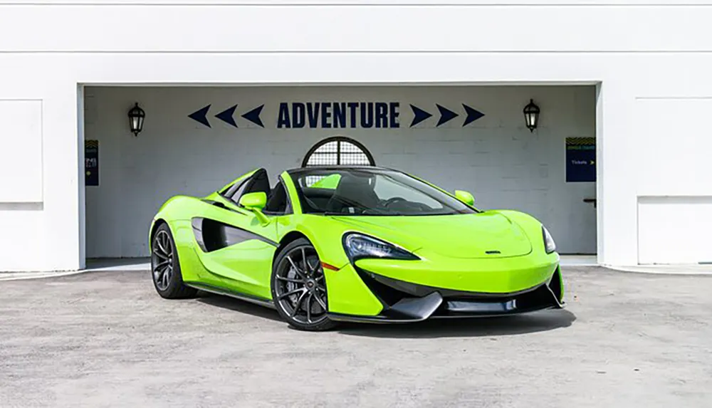 A bright green sports car is parked in front of a white garage with the word ADVENTURE and arrows pointing right above the door