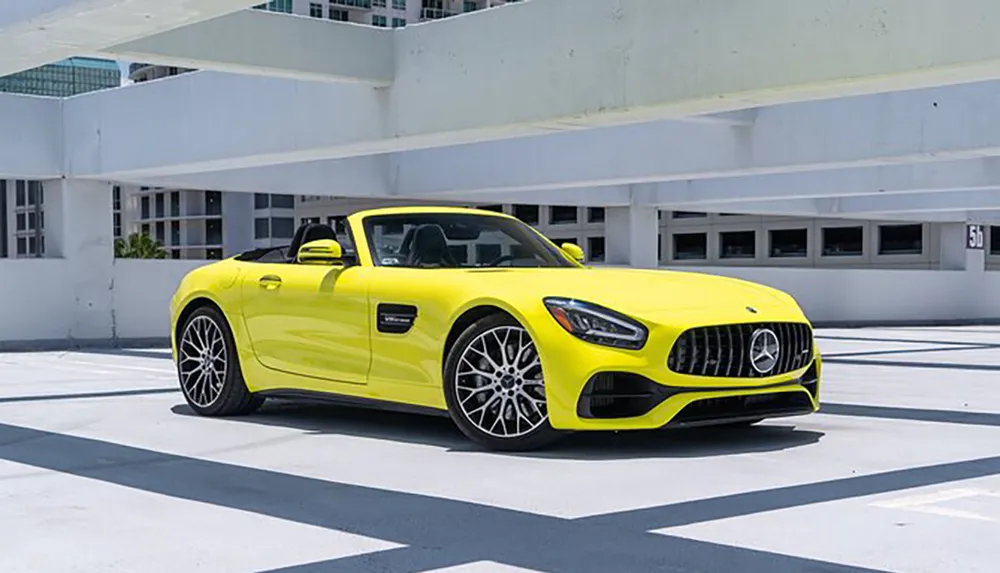 A bright yellow luxury convertible sports car is parked in an open-air parking structure