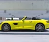 A bright yellow luxury convertible sports car is parked in an open-air parking structure