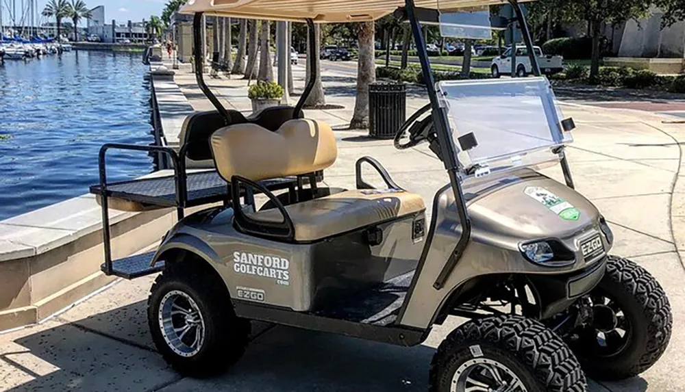 A golf cart is parked near a marina with a clear sky reflected on its shiny surfaces