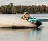 Two individuals are enjoying a ride on a jet ski creating a splash of water behind them