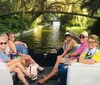 A group of people is enjoying a boat ride on a tree-lined canal