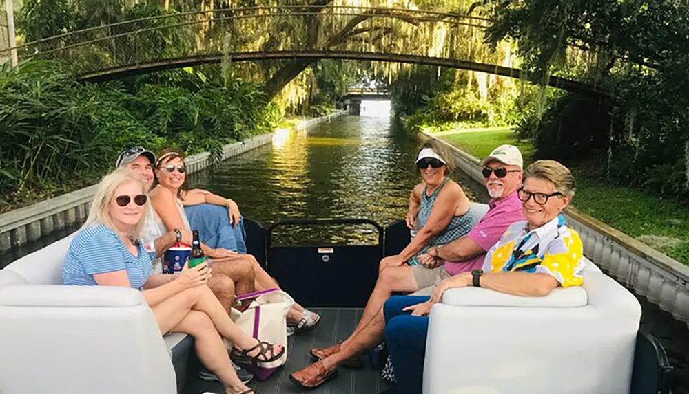 A group of people is enjoying a boat ride on a tree-lined canal