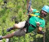 A man wearing a helmet and harness is enjoying a zipline ride through a forest