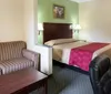 The image shows a neatly arranged hotel room with a bed office chair desk and other typical furnishings