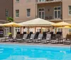 The image shows a hotels outdoor pool area with lounging chairs and umbrellas evoking a leisurely atmosphere for relaxation