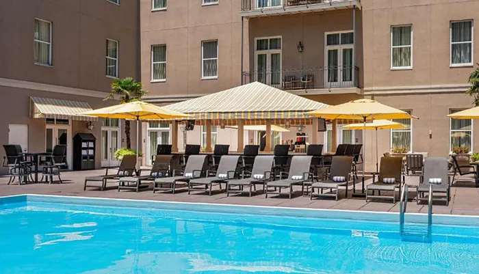 The image shows a hotels outdoor pool area with lounging chairs and umbrellas evoking a leisurely atmosphere for relaxation