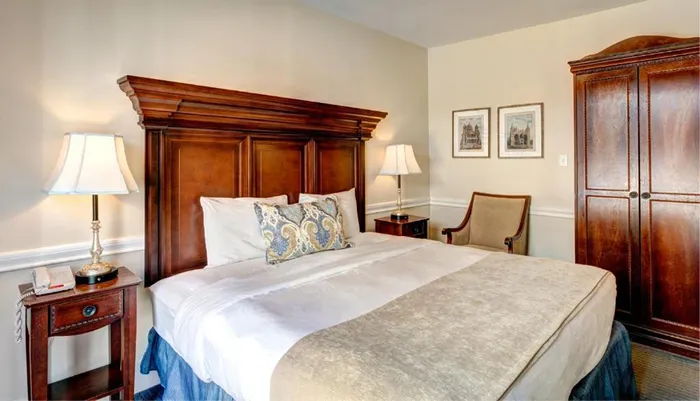 The image displays a neatly arranged bedroom with a large bed wooden furniture and elegant decor
