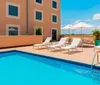 A sunny hotel pool deck with lounge chairs and umbrellas awaits guests for a relaxing day outdoors