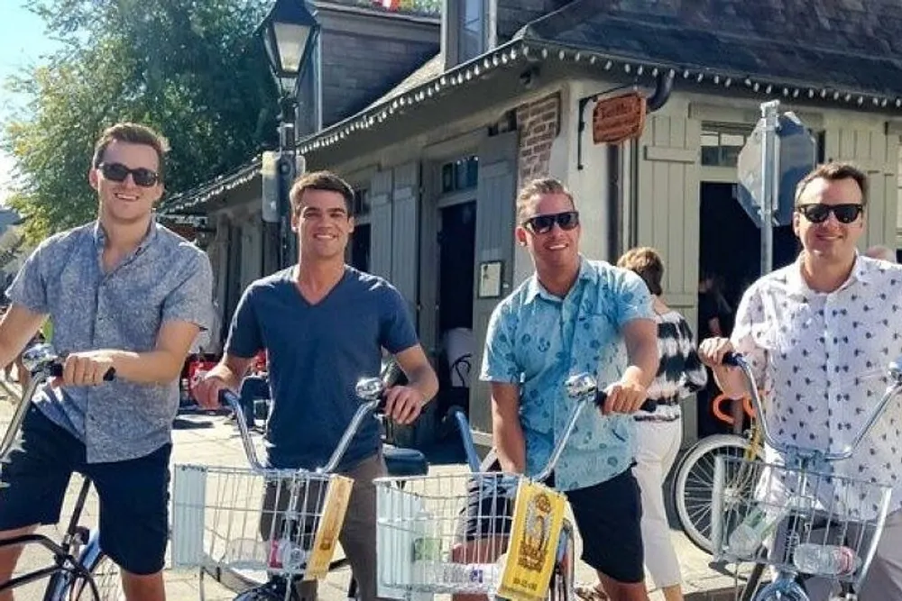 Four men are smiling and posing with bicycles on a sunny day likely enjoying a leisurely outing