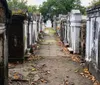 The image shows a pathway flanked by rows of weathered above-ground tombs or mausoleums in what appears to be an old cemetery