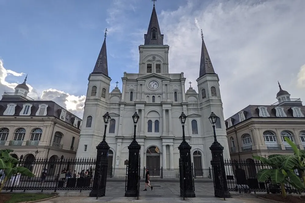 The image shows the iconic St Louis Cathedral located in the French Quarter of New Orleans Louisiana with people walking by and enjoying the ambiance of the historic area
