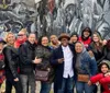 A group of cheerful people is posing for a photo in front of a grayscale mural