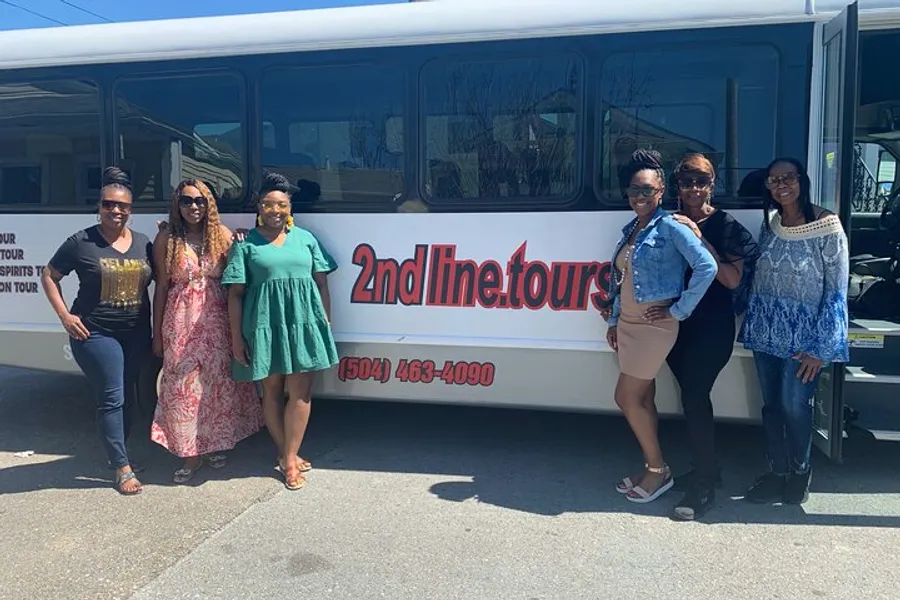 A group of smiling people is posing alongside a 2ndlinetours bus, suggesting they are either embarking on or have completed a tour.