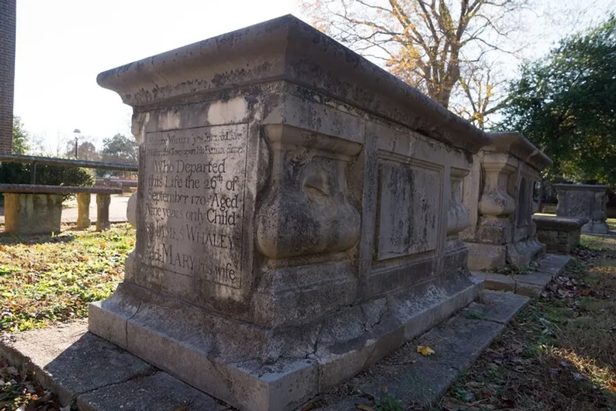 The image shows an aged, ornate tombstone in a cemetery with inscriptions that have partly weathered away over time.