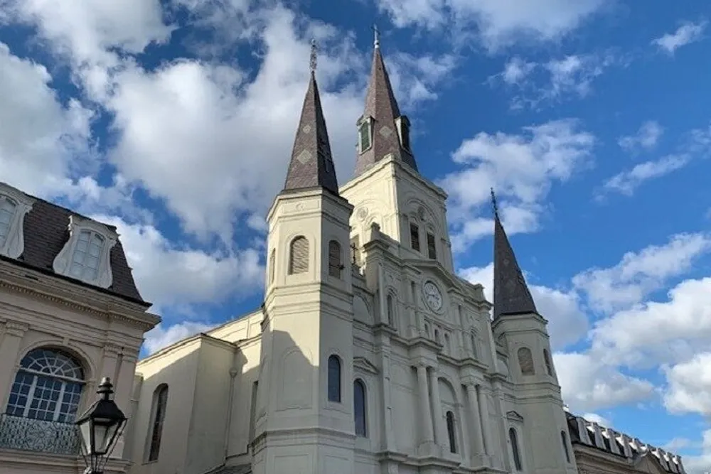 An elegant white church with two steeples rises against a blue sky dotted with clouds