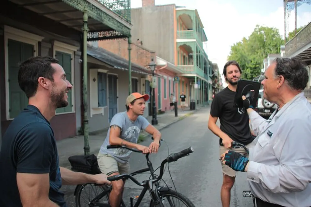 Three men appear engaged in a lively and friendly conversation on a historic street with two of them on bicycles and the other gesticulating passionately