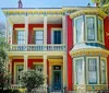 The image showcases a vibrant two-story Victorian house with a bay window and a colorful facade