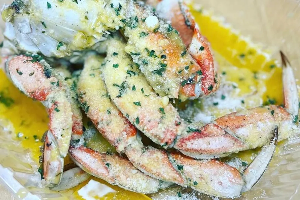 The image shows a dish of seasoned crab legs with herbs and melted butter
