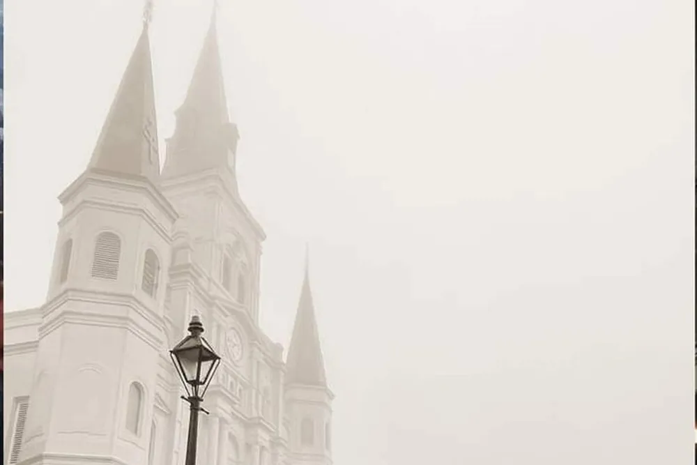 The image shows a church with spires shrouded in fog creating a serene and mysterious atmosphere