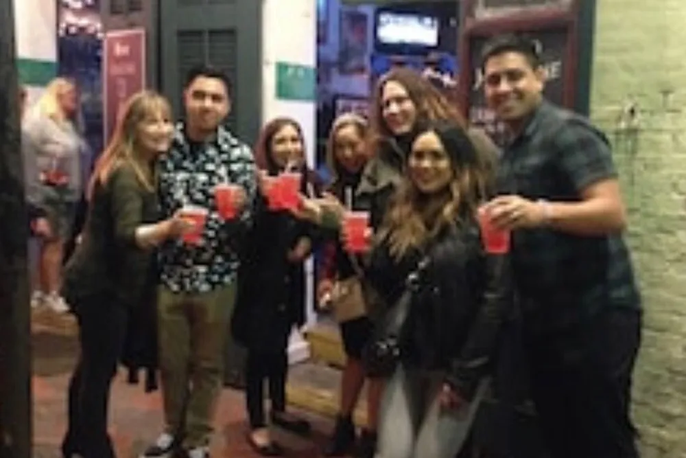 A group of people are posing for a photo on a street while holding red cups suggesting they might be at a social outing or party