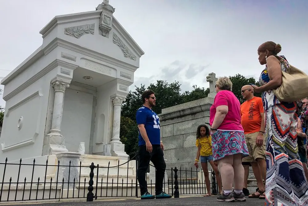 A group of people are standing in front of a white monument structure on a cloudy day