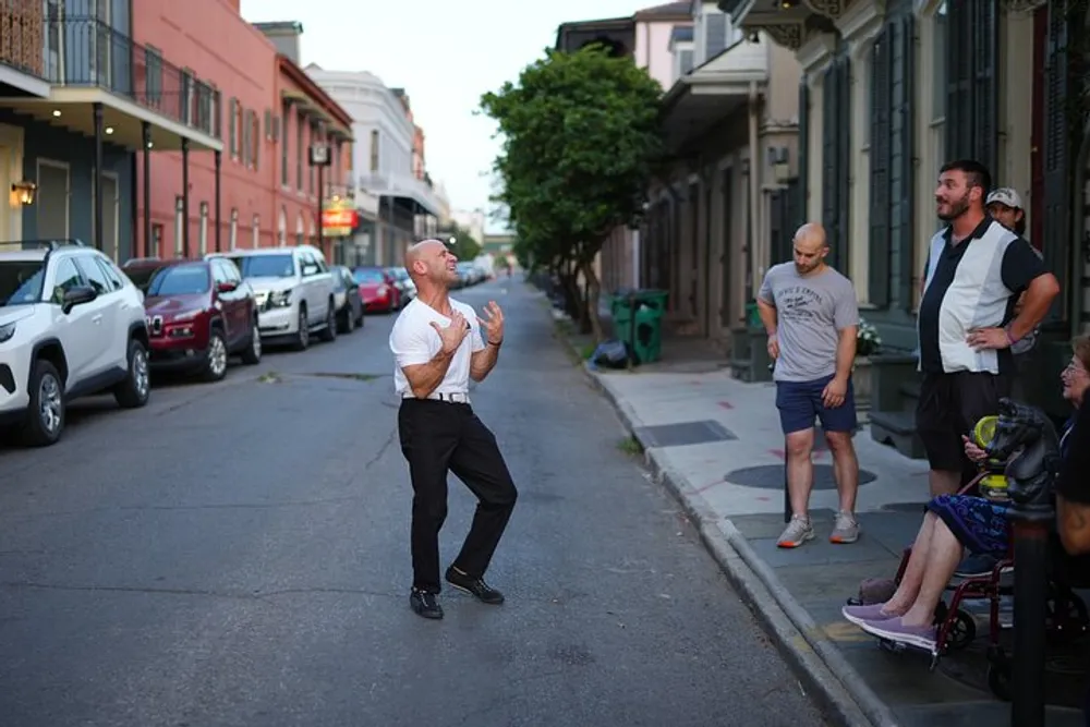 A man is energetically dancing in the street while onlookers watch creating a scene of urban entertainment