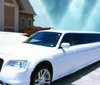 A white stretch limousine is parked under a clear blue sky