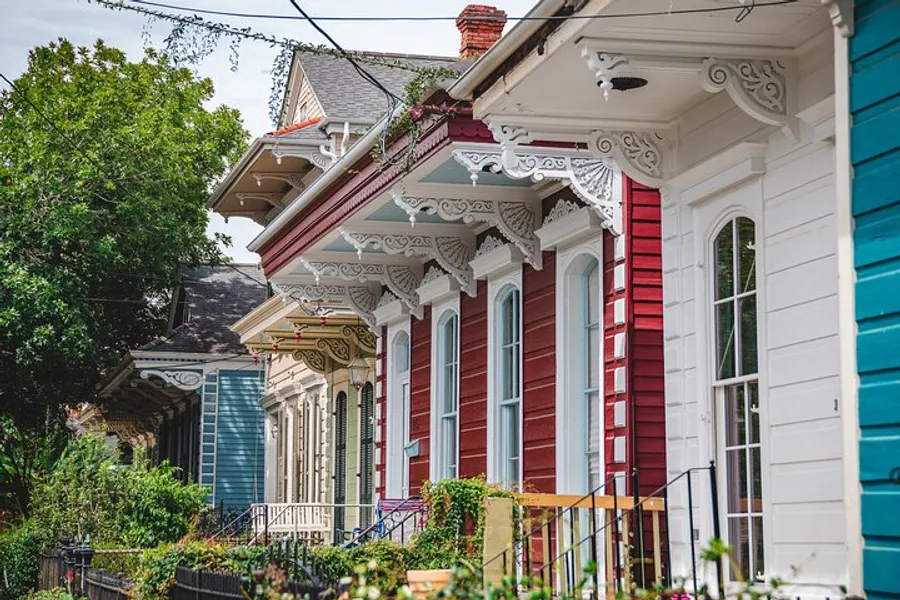 A row of colorful houses with ornate, Victorian-style trim and welcoming porches lining a sunny street.