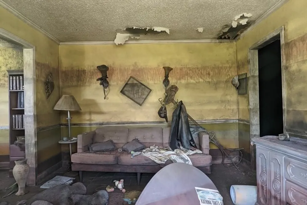 An abandoned living room displaying signs of decay and neglect with debris scattered on the floor and peeling paint on the walls