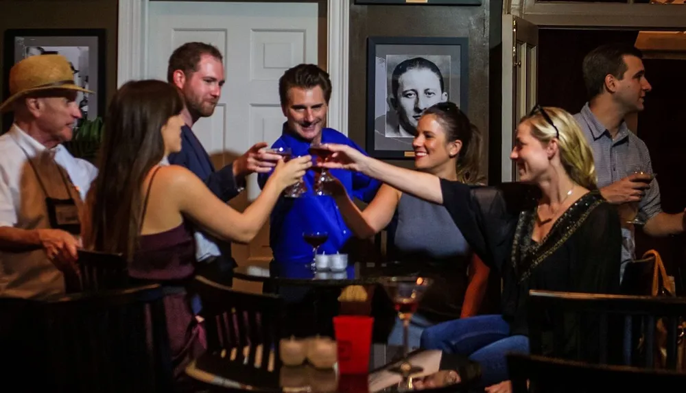 A group of smiling people are toasting with drinks in a social gathering
