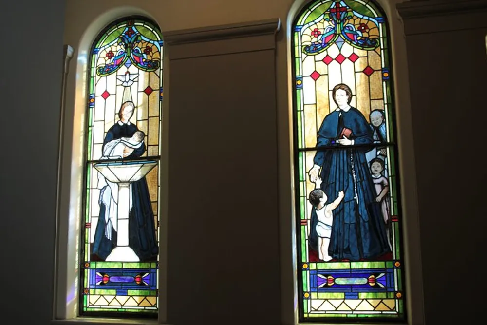 The image shows two stained glass windows each depicting figures that appear to embody caring and nurturing themes possibly reflecting religious or moral virtues
