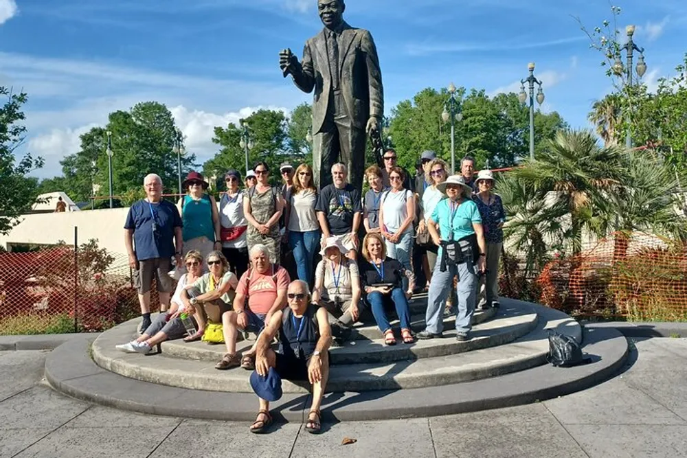 A group of people pose for a photo in front of a statue under a clear blue sky