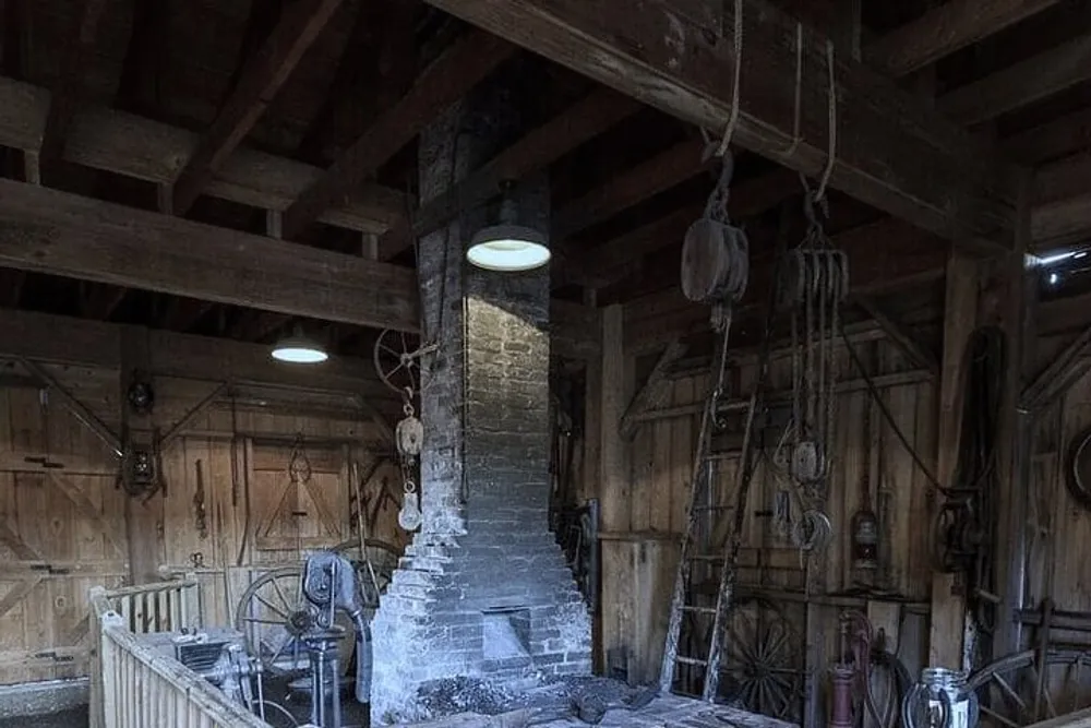 The image shows a rustic interior possibly a historic or old-fashioned workshop with wooden walls a brick chimney block and tackle and various old tools and equipment