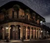 The image features a corner view of a historic two-story building at night with a classic wrought-iron balcony and deserted streets suggesting a quiet possibly eerie atmosphere