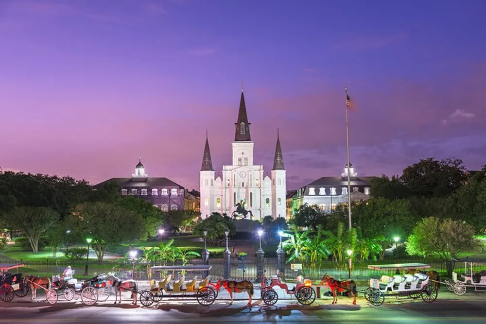 The image shows a twilight scene featuring the iconic St Louis Cathedral with a line of horse-drawn carriages in the foreground at Jackson Square in the French Quarter of New Orleans