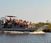 A group of passengers are enjoying a ride on an airboat skimming over the water with lush green foliage in the background