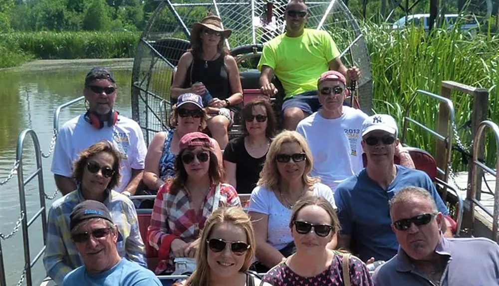 A group of people are smiling for a photo while seated in tiers on what appears to be an airboat tour