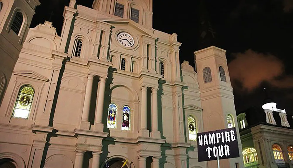 The image shows a church at night with illuminated stained glass windows alongside a sign advertising a Vampire Tour