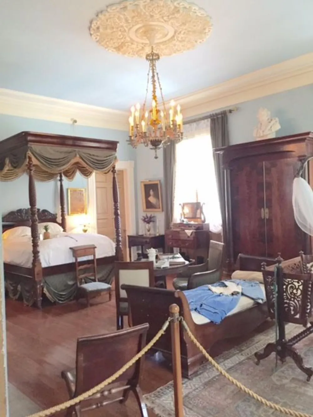 The image shows a Victorian-style bedroom with antique furniture ornate decorations and is cordoned off suggesting it might be part of a museum or historic home tour