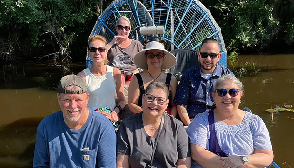 A group of seven people pose for a photo on an airboat during what appears to be a swamp tour