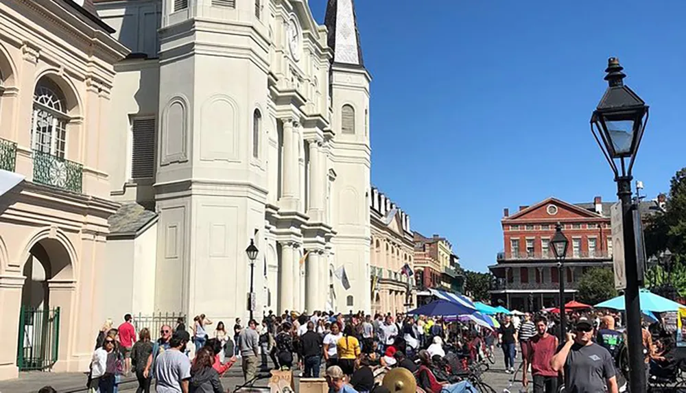 This image shows a bustling street scene with a crowd of people and street vendors in front of an iconic church building with historical architecture typical of a lively urban tourist destination