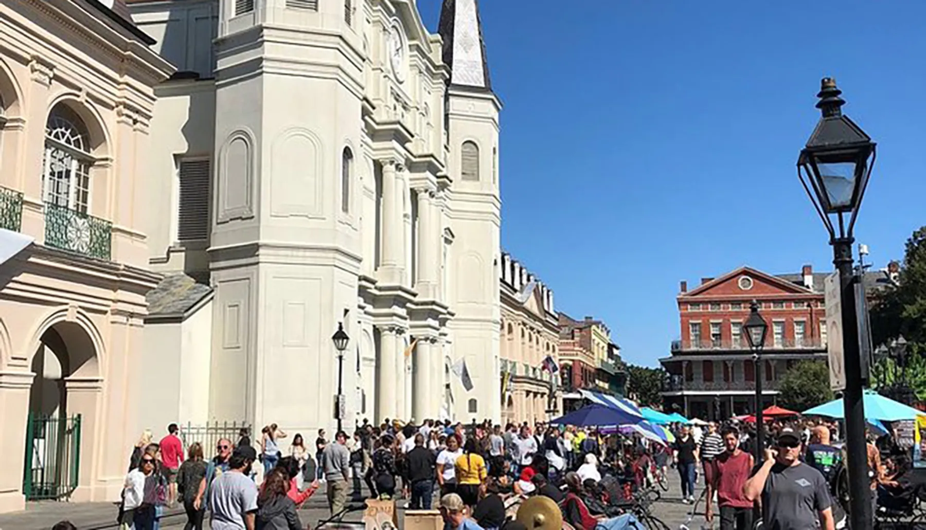 This image shows a bustling street scene with a crowd of people and street vendors in front of an iconic church building with historical architecture, typical of a lively urban tourist destination.