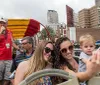 A red double-decker City Sightseeing bus with tourists on the top deck is driving through a busy street in New Orleans