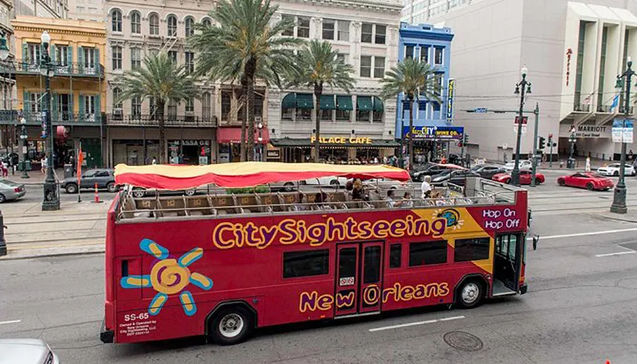 A red double-decker City Sightseeing bus with tourists on the top deck is driving through a busy street in New Orleans.