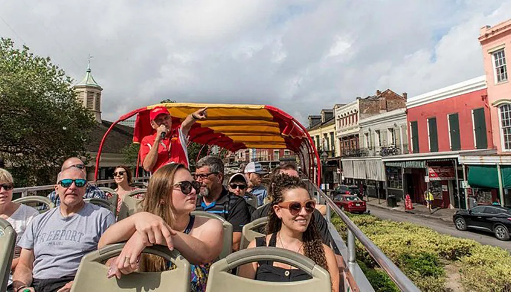 Passengers are enjoying a guided tour on an open-top double-decker bus traveling through a city with historic buildings