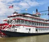 The image depicts the City of New Orleans riverboat a traditional paddlewheel steamboat docked on the water under a clear sky with American and state flags flying atop
