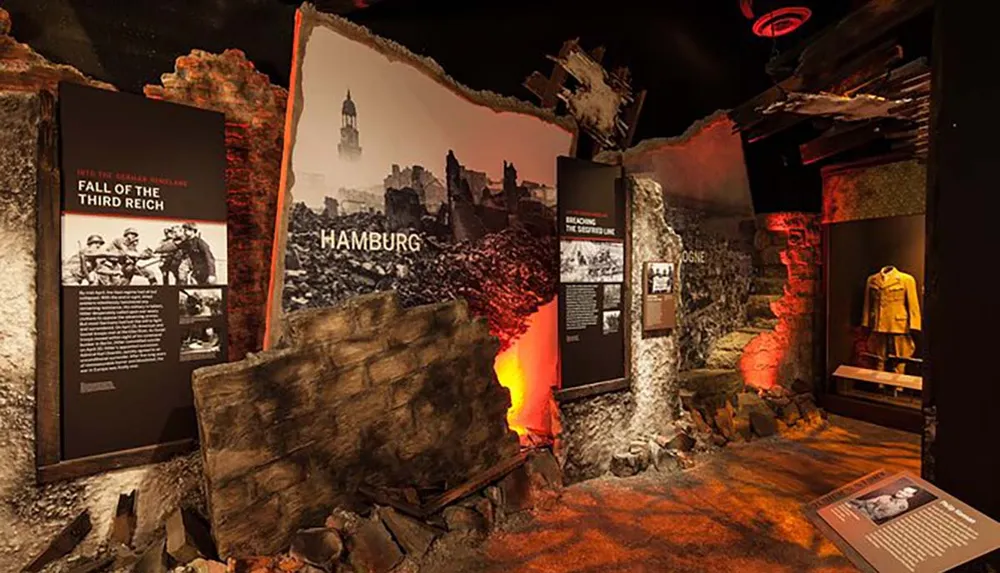 This image depicts an immersive museum exhibit focused on the Fall of the Third Reich with informative panels historical photographs and atmospheric design elements meant to create an engaging educational experience