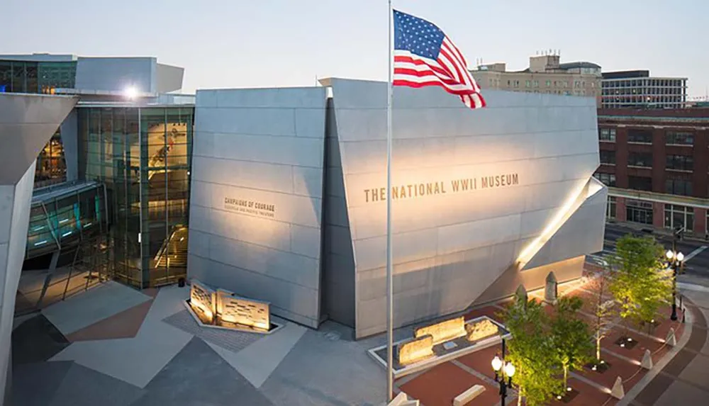 This image shows an exterior view of The National WWII Museum with an American flag flying in front highlighting its modern architecture and the museums dedication to the history of World War II